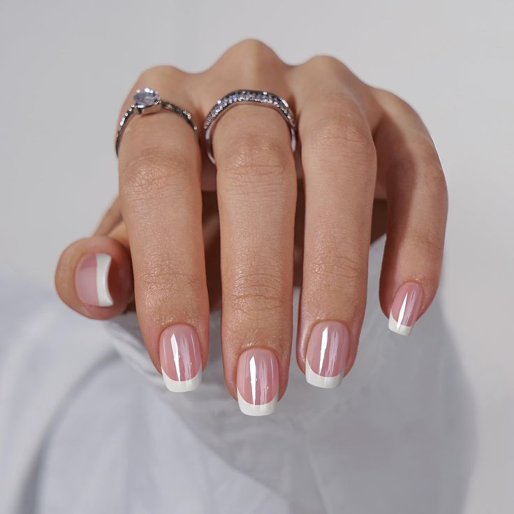 Chic Soft Pink and White French Manicure with Delicate Ring Accents.