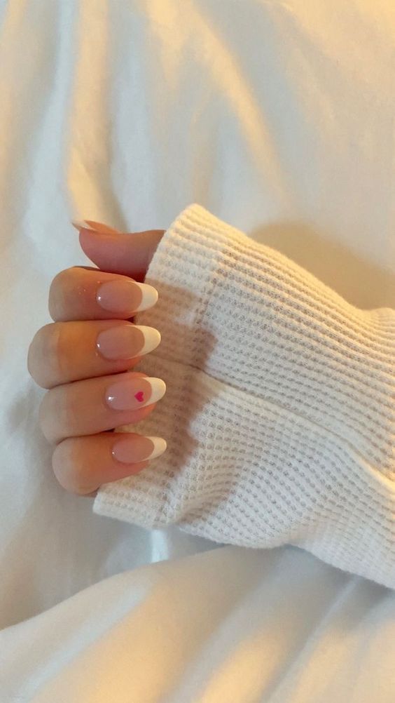 Chic French Manicure with Soft Pink Base, White Tips, and Playful Heart Detail.