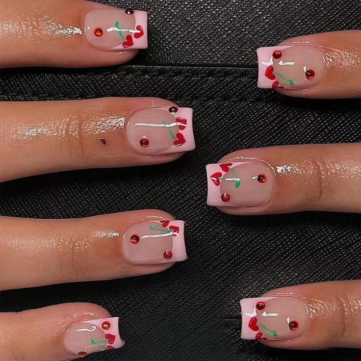 Whimsical Pastel Pink Nail Design with Cherry Motifs and Gem Accents.