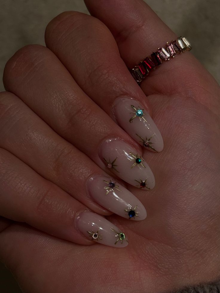 Elegant Beige Nail Design with Starburst Patterns and Colorful Gemstone Accents