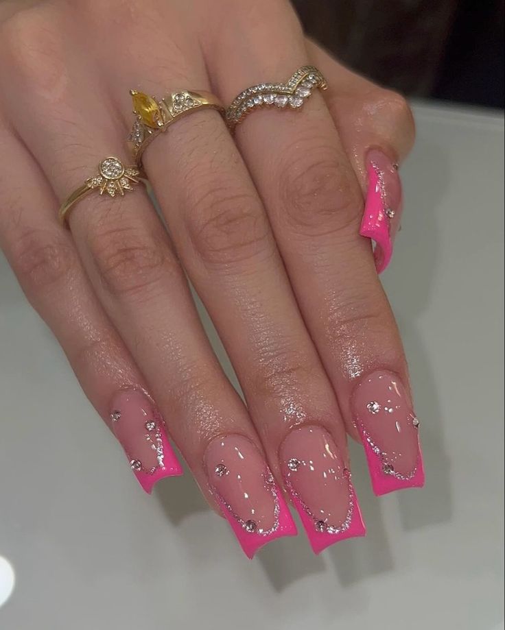 Chic Nail Design: Vibrant Pink Tips with Shimmering Rhinestones and Gold Rings.