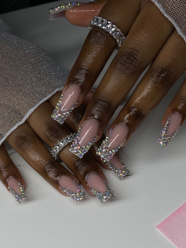 Elegant Long Nude Acrylic Nails with Sparkling Rhinestone Tips and Chic Accents.