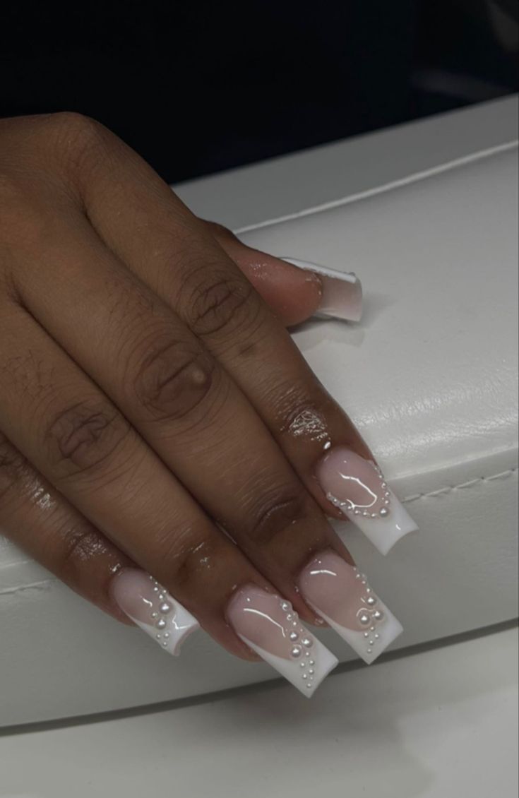 Chic Nude Nail Design with White French Tips and Pearl Accents for Elegant Occasions.