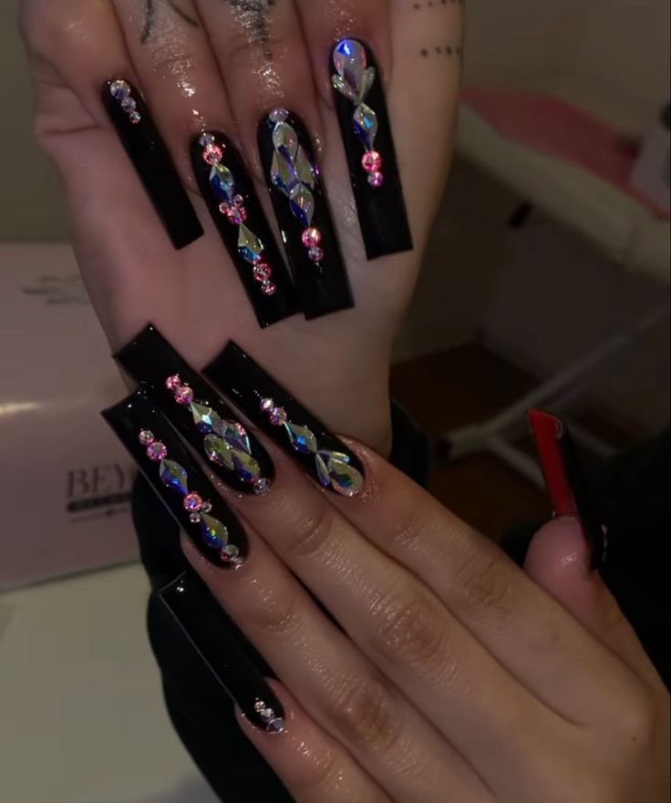 Glamorous Black Nail Art Enhanced with Vibrant Gemstones and Shimmering Accents.