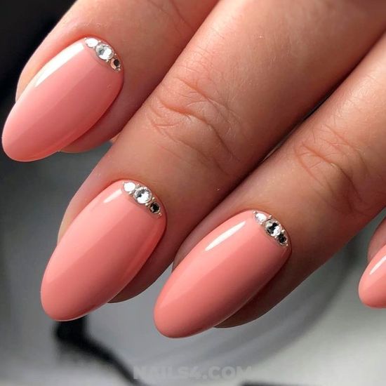 Chic Almond-Shaped Nails with Glossy Peach Polish and Silver Cuticle Studs.