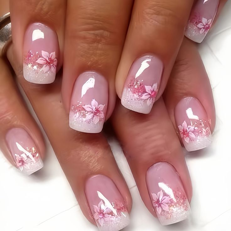 Romantic Soft Pink Gradient Nail Design with Floral Accents and Glitter Tips.