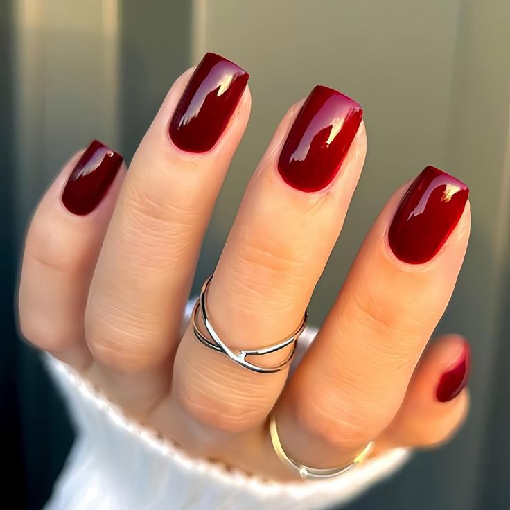 Elegant Glossy Burgundy Square Nails: A Striking Aesthetic Enhanced by Dainty Rings.