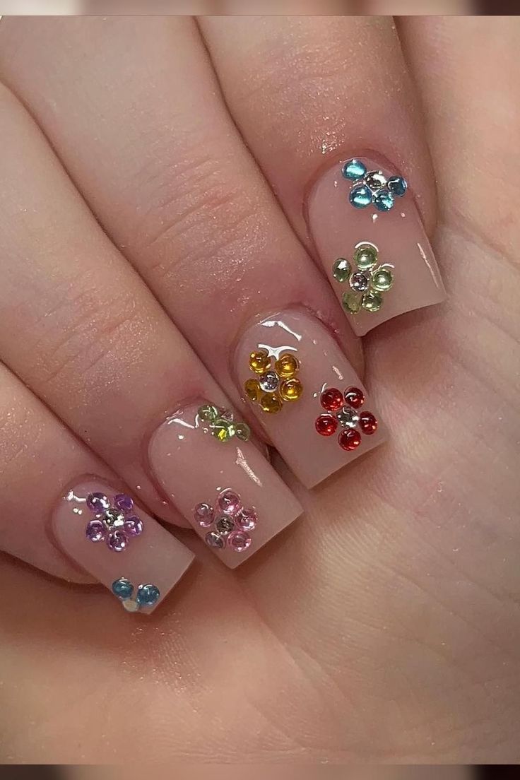 Playful Nail Design: Nude Base Embellished with Colorful Gem-Like Flowers.