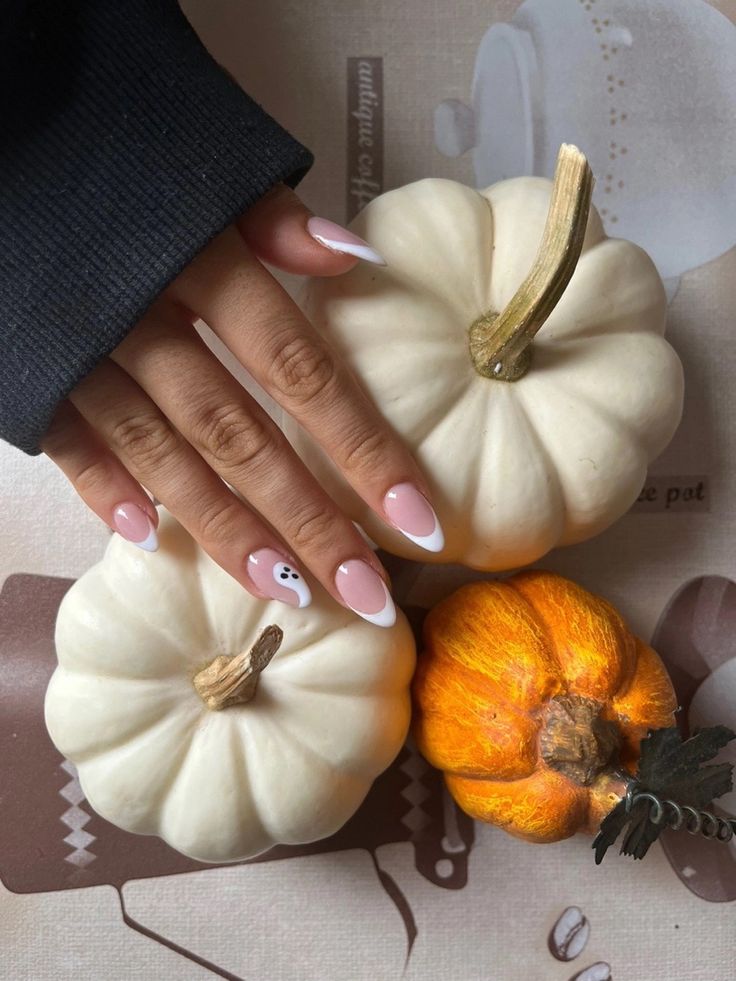 Enchanting Halloween Nail Design: Soft Pink Base with White Tips and Playful Ghost Detail Amidst Autumn Pumpkins.