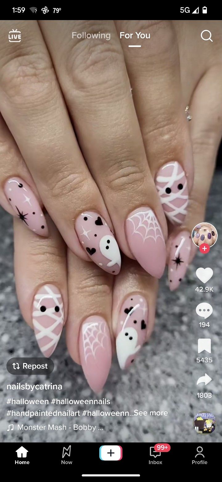 Whimsical Halloween Nail Art: Playful Ghosts, Webs, and Stars on Soft Pink and White Backgrounds.