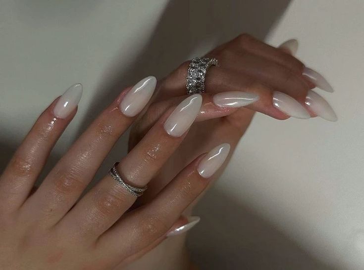 Chic Almond-Shaped Ombre Nails: Glossy White to Pink Transition Perfectly Paired with Silver Rings.