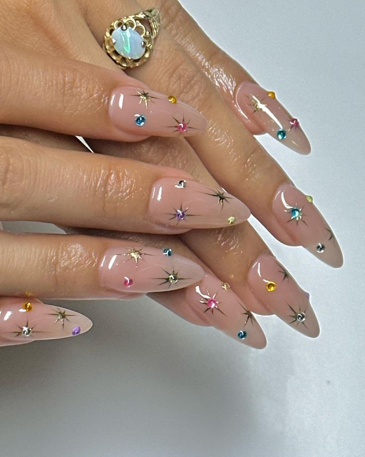 Chic Almond-Shaped Nail Art: Dazzling Gems and Star Motifs on a Nude Base.