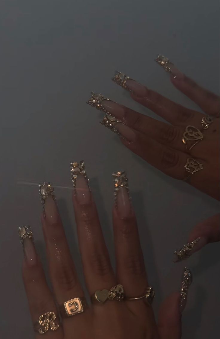 Luxurious Long Tapered Nails with Gold Embellishments and Delicate Ring Accents.