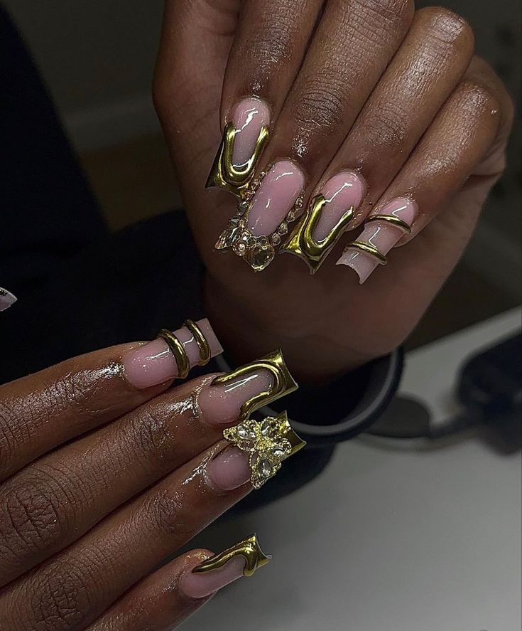 Glamorous Nail Design with Nude and Gold Accents Featuring Intricate Gem Embellishments