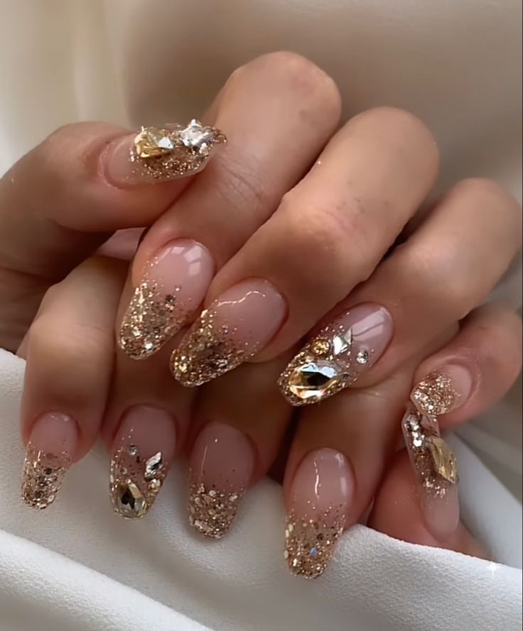 Elegant Nude and Glitter Gold Nail Design with Opulent Jewel Accents.