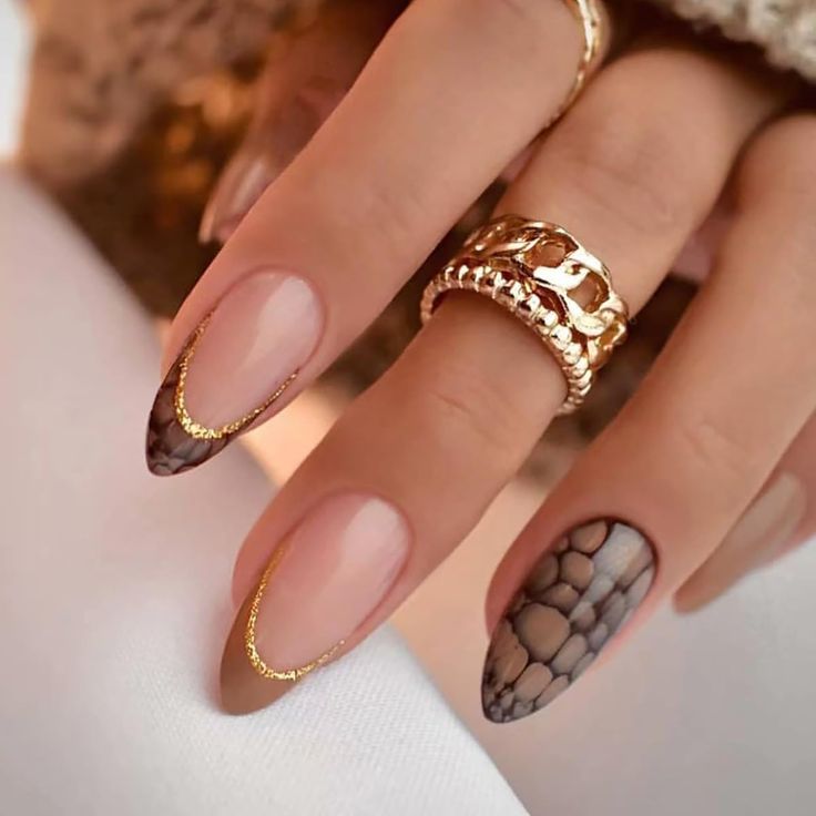 Chic Nail Design: Nude and Patterned Elegance with Golden Accents and Stylish Rings.