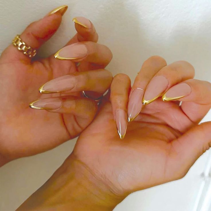 Chic Almond-Shaped Nails with Sheer Nude Base and Gold Tips, Perfectly Accented by Delicate Rings.