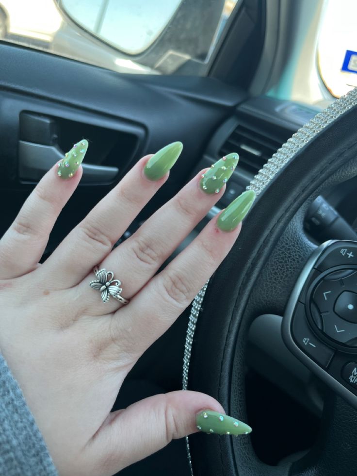 Vibrant Green Acrylic Nails with Delicate White Dots and Floral Ring for a Trendy Look.