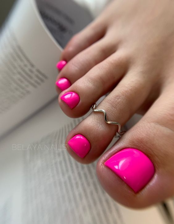 Bold Pink Toenails with Glossy Finish and Elegant Silver Toe Ring for a Playful Summer Look