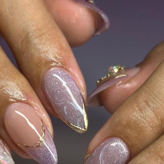 Elegant Blush and Shimmering Lavender Nail Design with Gold Accents and Rhinestones.