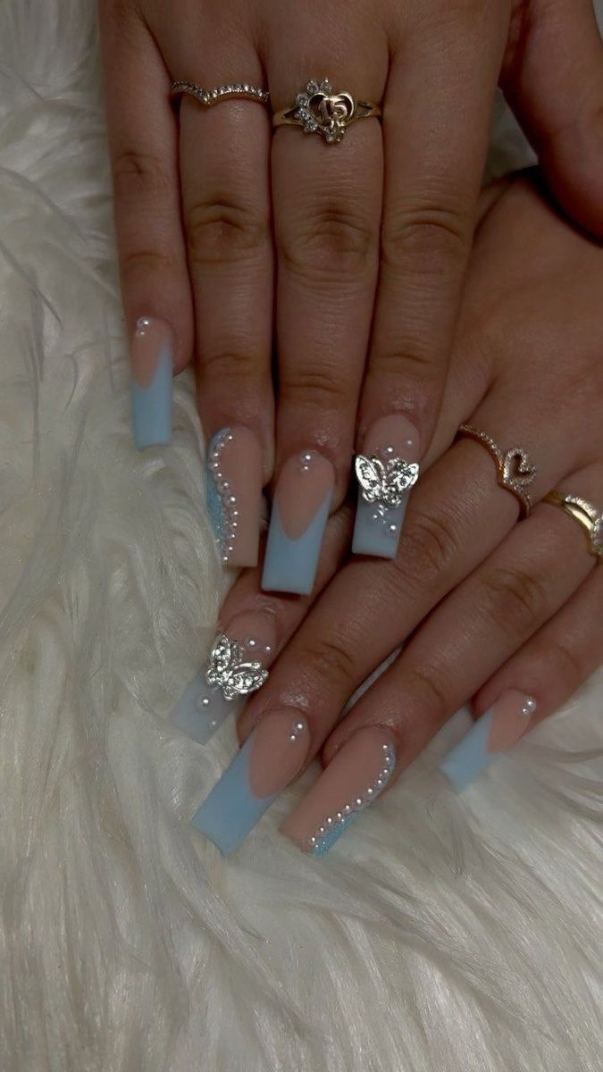 Sophisticated Nude and Pastel Blue Nail Design with Silver Butterfly Accents and Rhinestones