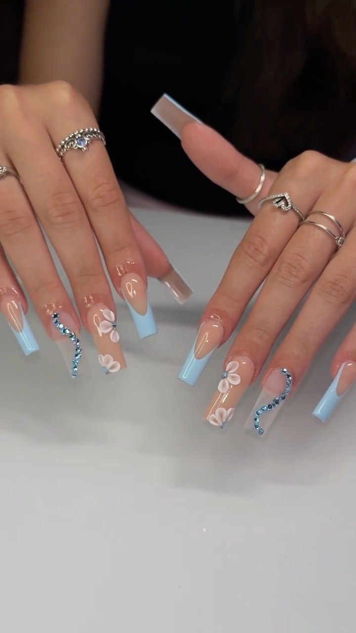 Elegant Nail Design: Soft Blue and Neutrals with Floral Accents and Sparkling Embellishments