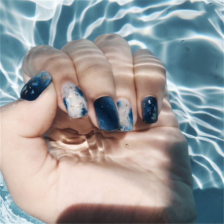 Elegant Deep Navy and Shimmering Gold Nail Design with Captivating Marble Effect.