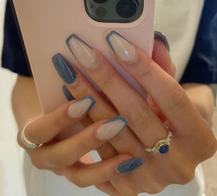 Chic Nail Design: Opaque Dark Blue and Translucent Nude with Almond-Square Shape, Enhanced by Delicate Rings.