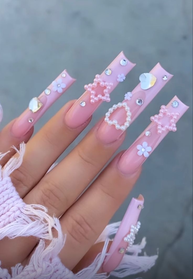 Charming Soft Pink Nail Design with Playful Embellishments and Glamorous Accents.