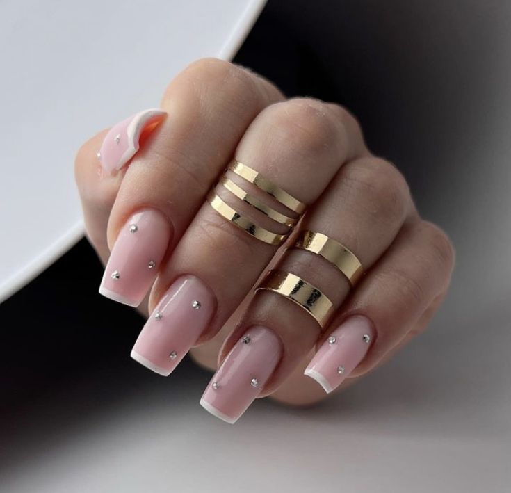 Sophisticated Soft Pink Nail Design with French Tips and Sparkling Silver Studs.