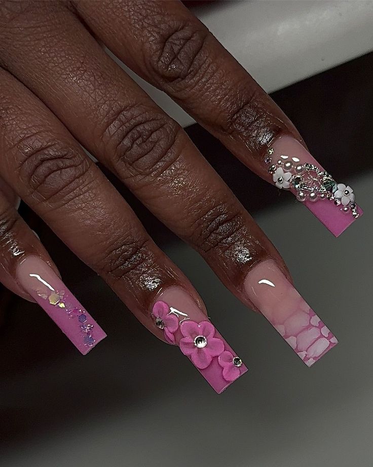 Chic Vibrant Pink Acrylic Nails with Floral Designs and Sparkling Embellishments.