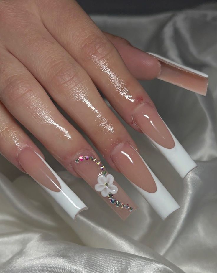 Chic Nude and White Nail Design with Floral Accents and Glamorous Rhinestones