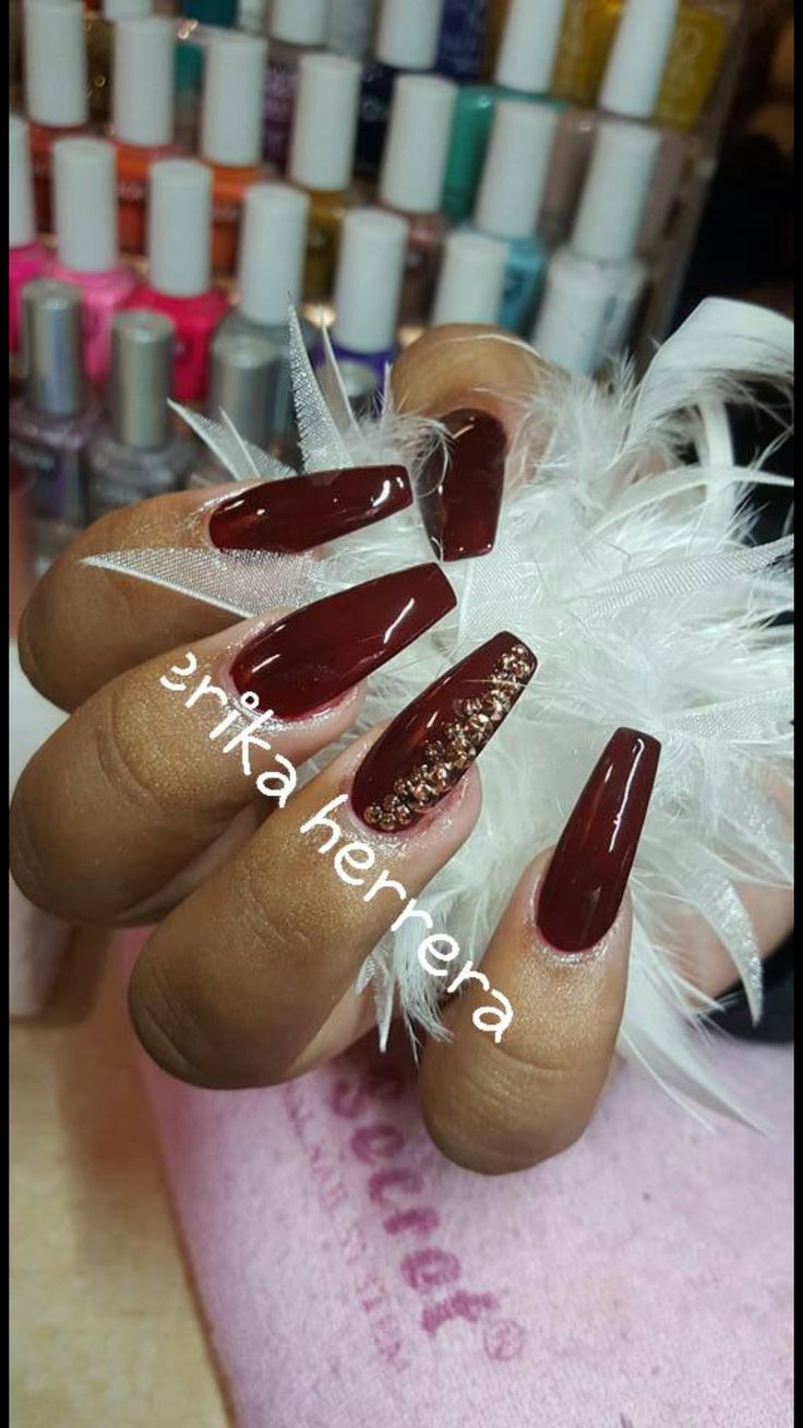 Elegant Deep Burgundy Nail Design with Shimmering Gold Accents and Oval Tips.