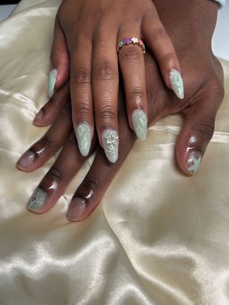 Sophisticated Mint Green Almond-Shaped Nails with Intricate Designs and Glossy Finish.