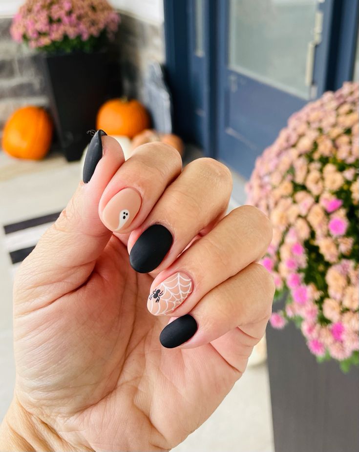 Chic Halloween Nails: Matte Black and Nude Design with Spider Web and Ghost Accents.