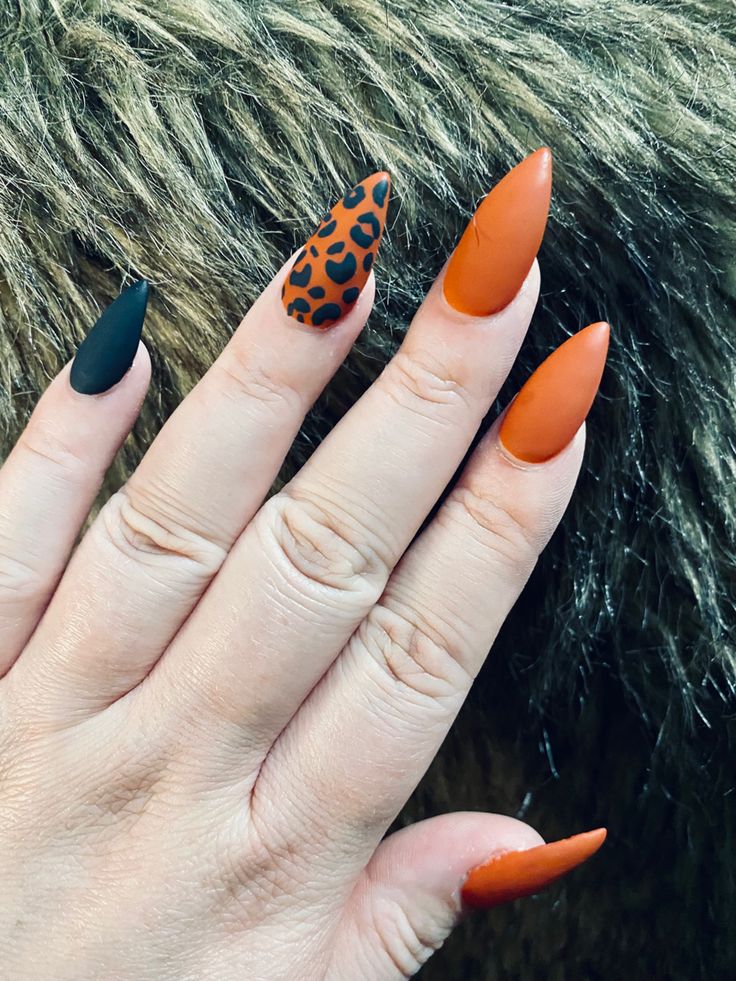 Bold and Stylish Almond-Shaped Nail Design with Matte Black, Vibrant Orange, and Leopard Print.