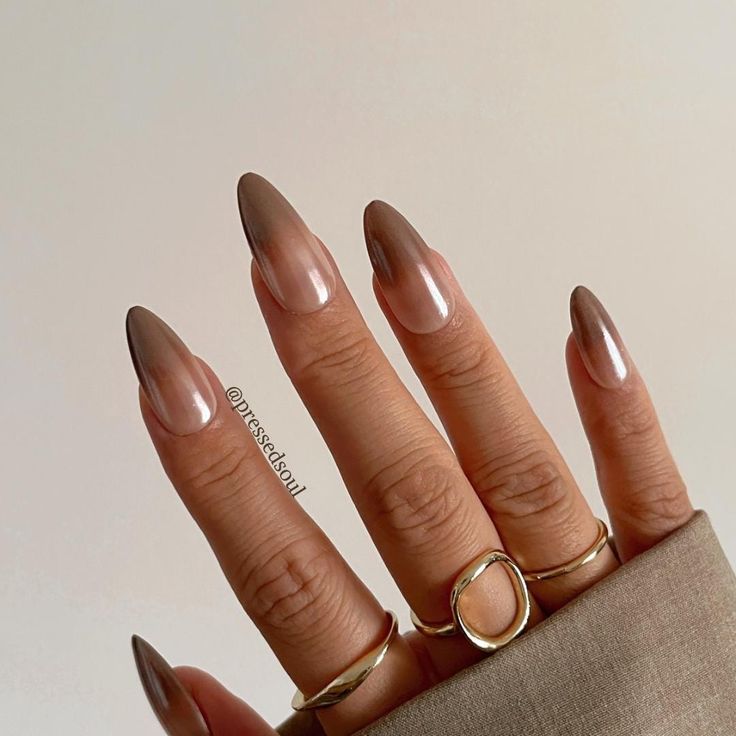 Elegant Almond-Shaped Gradient Nails in Nude to Brown, Accentuated with Delicate Gold Rings.