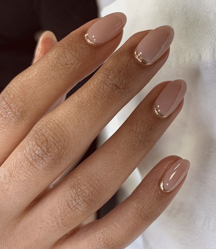 Sophisticated Almond-Shaped Nude Manicure with Glossy Finish and Gold Tips