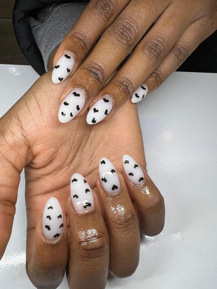 Whimsical Translucent White Nails with Delicate Black Heart Patterns and Glossy Finish.