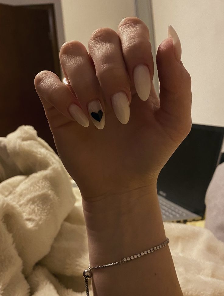 Refined Almond-Shaped Nails with Nude Base and Striking Black Heart Accent