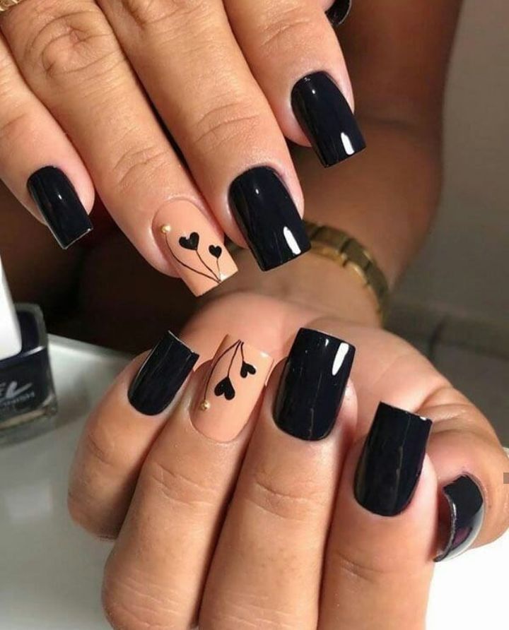 Chic Nail Design: Deep Black Polish with Minimalist Heart Motifs on a Nude Base.