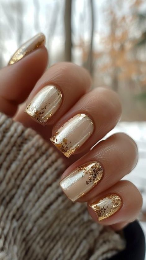 Sophisticated Beige Nail Design with Glossy Finish and Gold Glitter Accents.