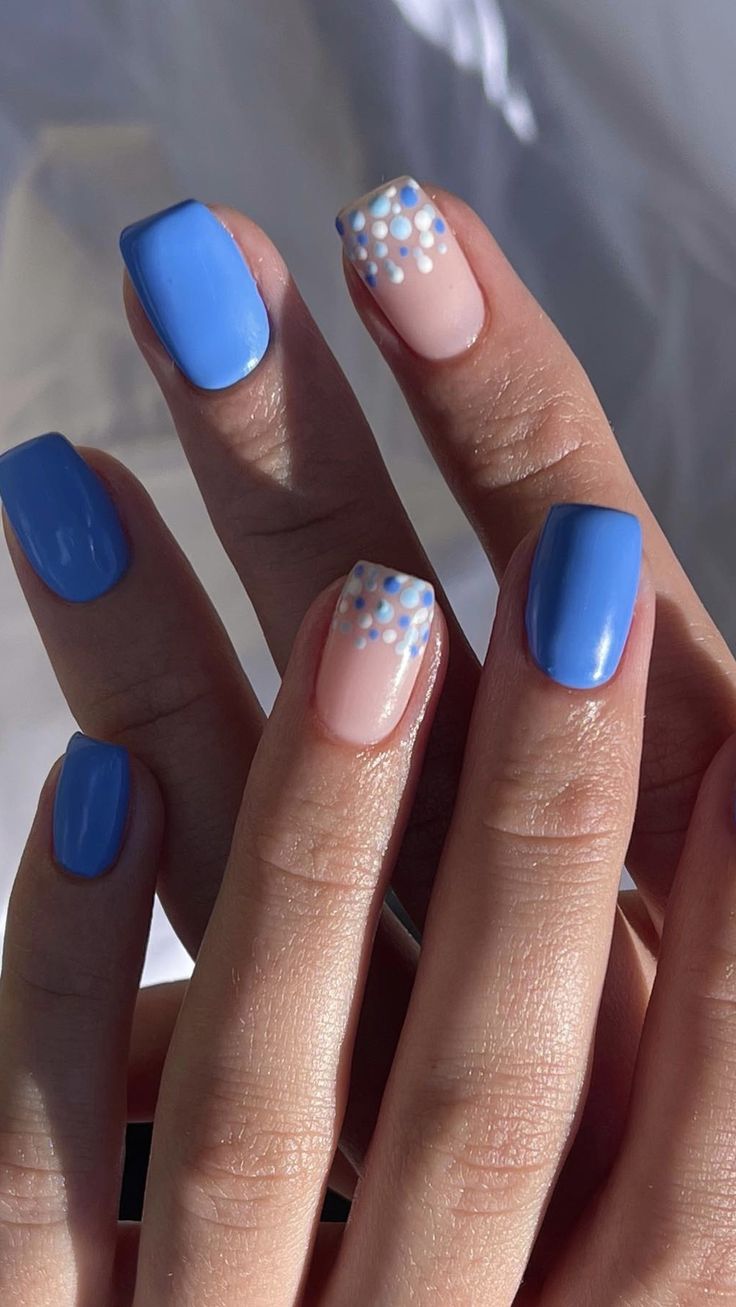 Vibrant Blue and Nude Nail Design with Playful Polka Dot Accent.