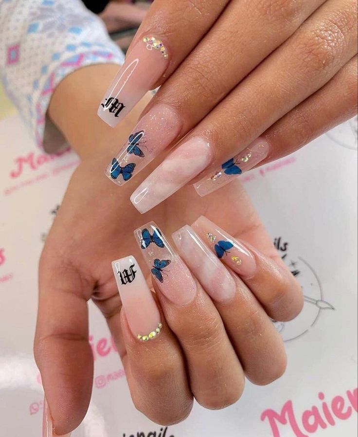 Sophisticated Nail Design with Natural Pink and Clear Acrylics, Intricate Blue Butterflies, and Delicate Gemstones.