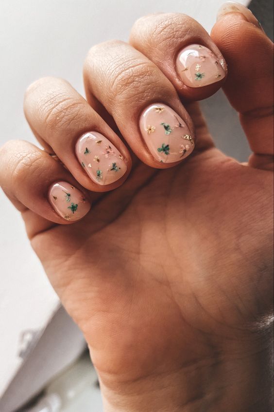 Elegant Nude Nail Design with Subtle Green Foliage and Gold Accents