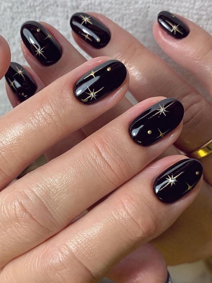 Sophisticated Black and Gold Nail Design with Intricate Star Patterns for Glamorous Occasions.