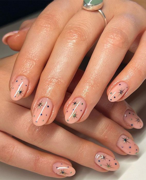 Elegant Nude Nail Design with Celestial Star Patterns and Gold Accent Sparkle