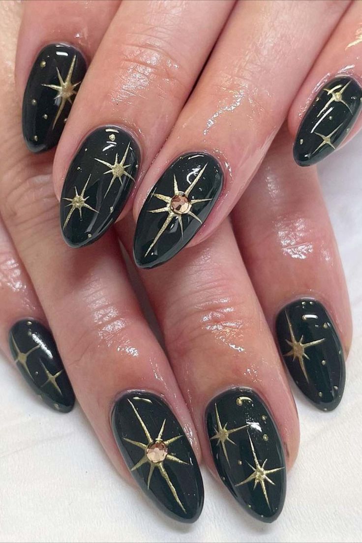 Glamorous Dark Green Nail Design with Gold Starbursts and Sparkling Gem Accent.