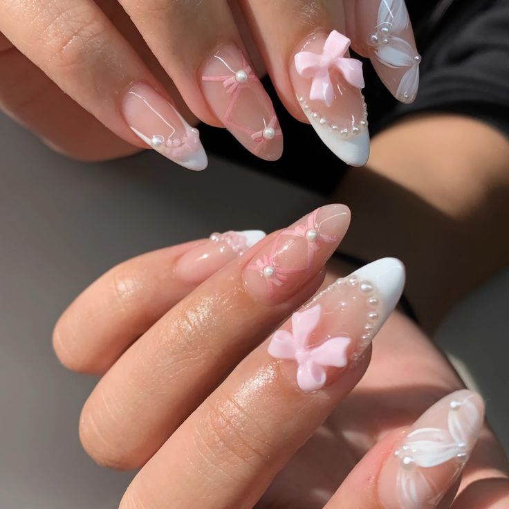 Chic Feminine Nail Design: Soft Pink and White with Floral Patterns and Embellishments.