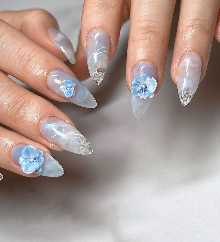 Delicate Light Blue Floral Nail Design with Modern Stiletto Shape and Metallic Details.